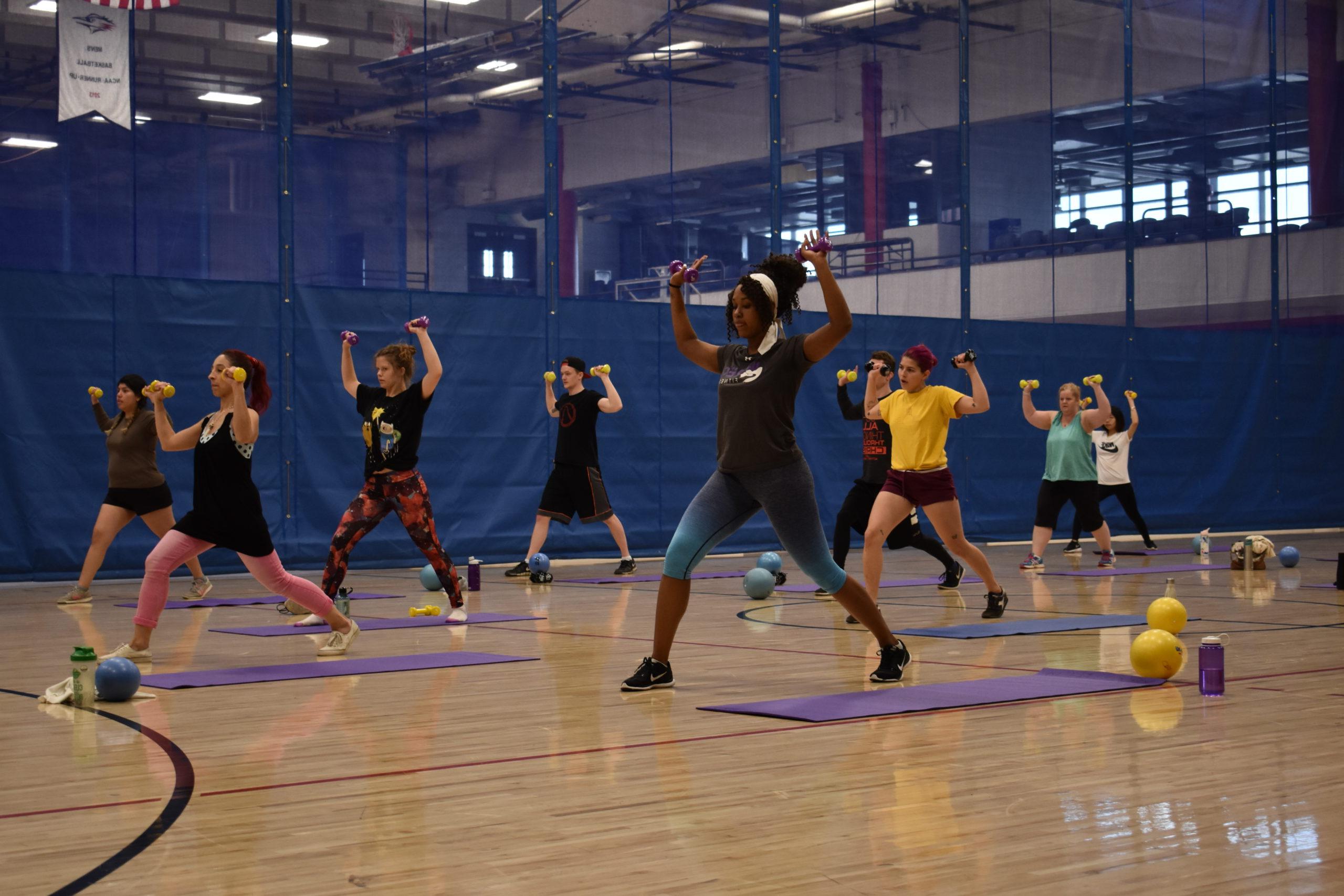 group fitness participants doing a lunging shoulder press